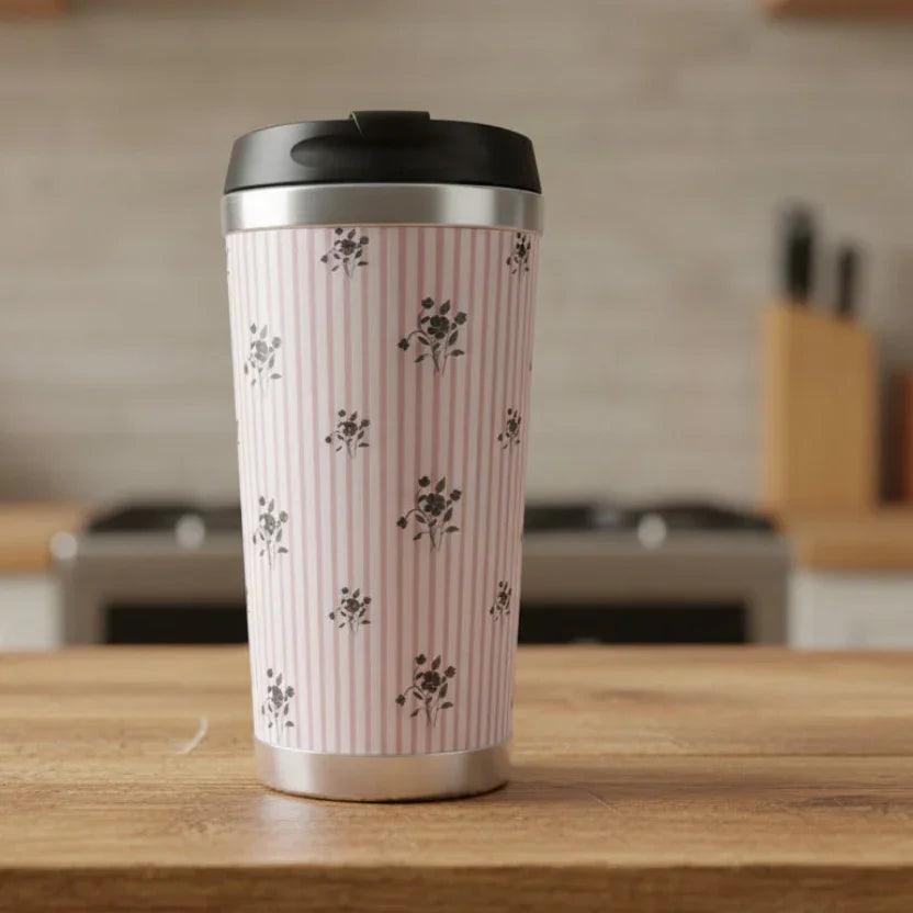 Pink floral striped travel mug with black lid on wooden kitchen counter
