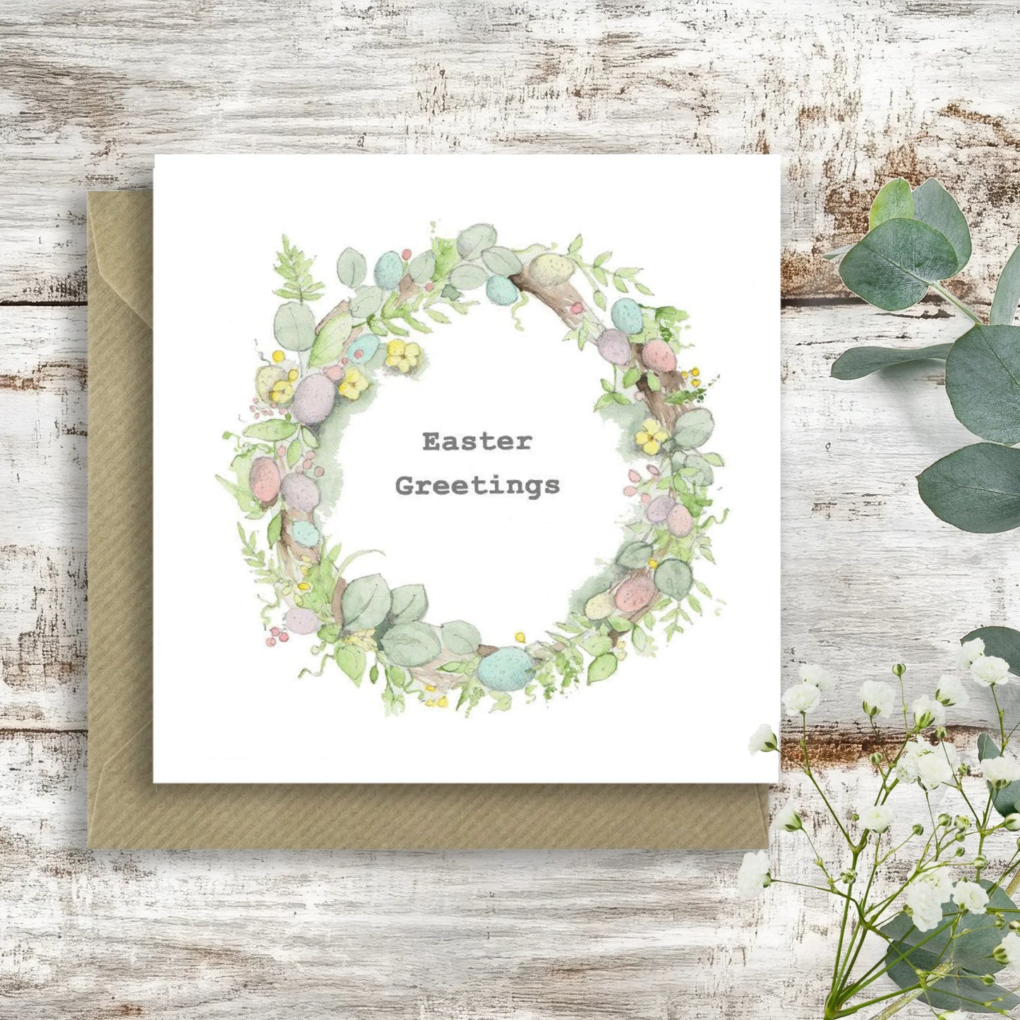 Easter greetings card with watercolor floral and egg wreath on rustic wooden background