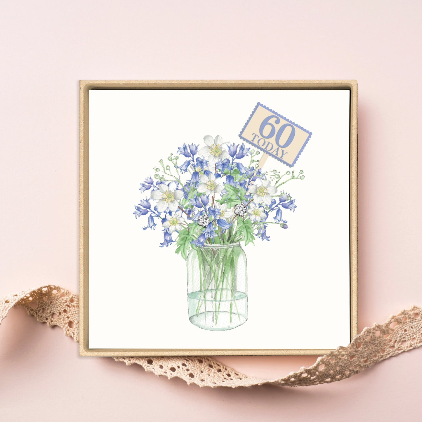 Boxed 60th birthday card with blue and white flowers in a glass jar on a pink background