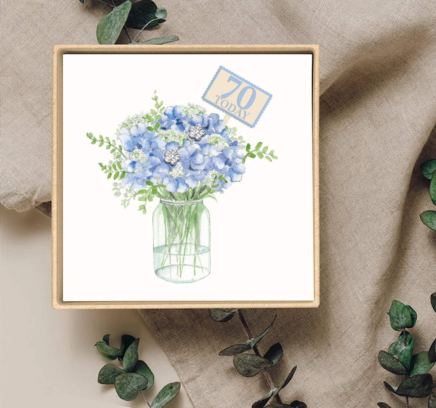 Gift box with watercolor blue flowers in a jar, '70 Today' tag, floral earrings display