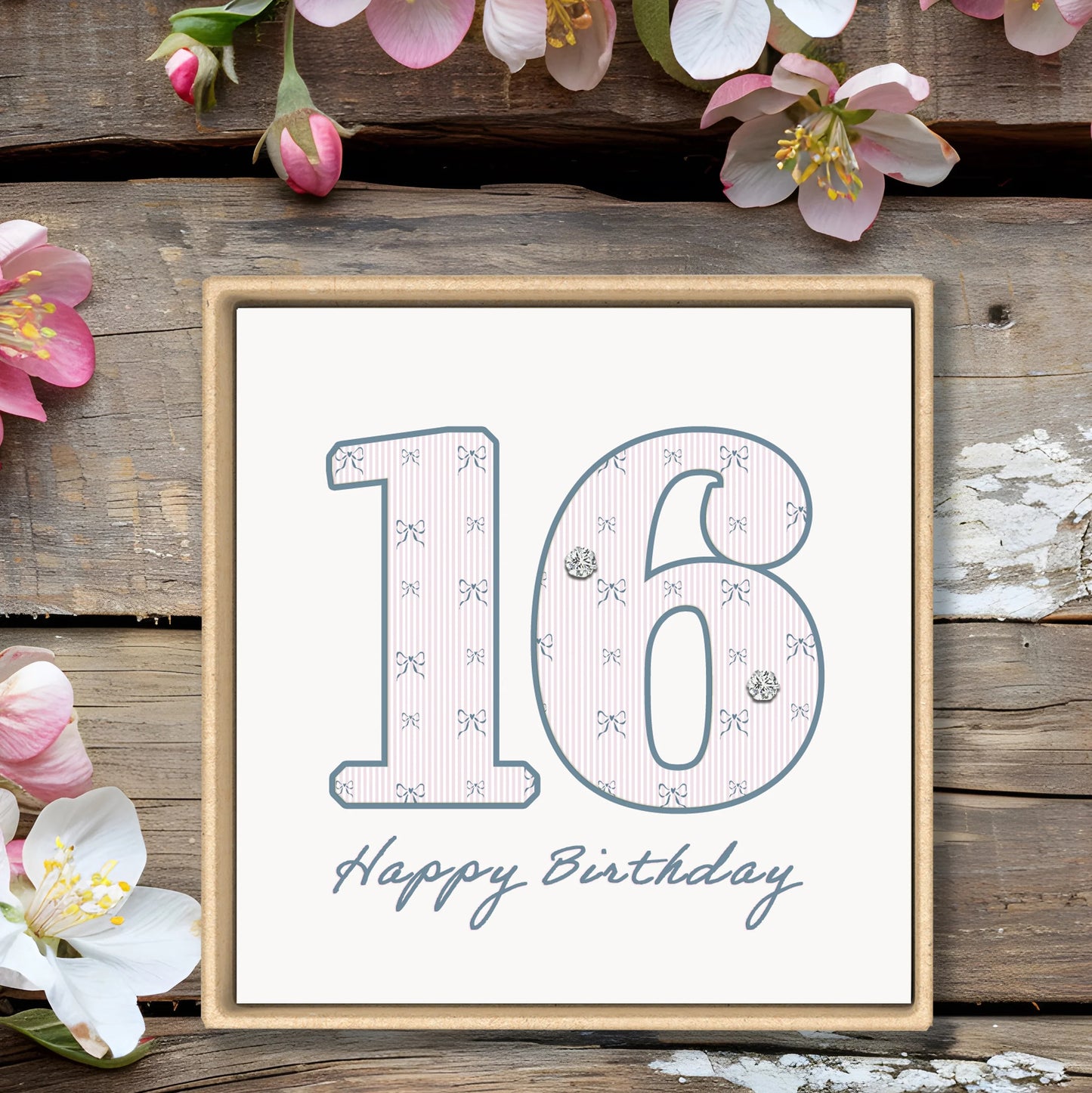 16th birthday card with floral accents, wooden background, and elegant bow pattern