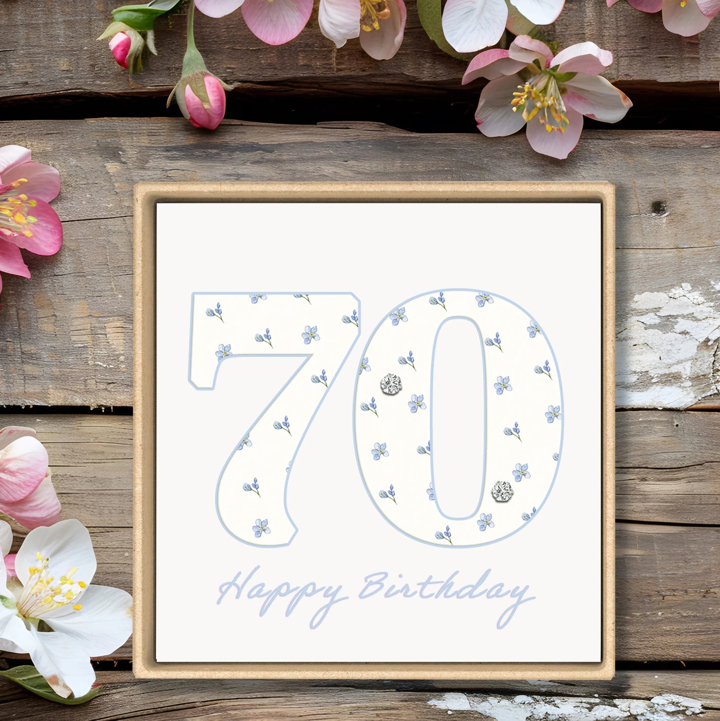 70th birthday card with blue floral design on rustic wood and pink flowers background