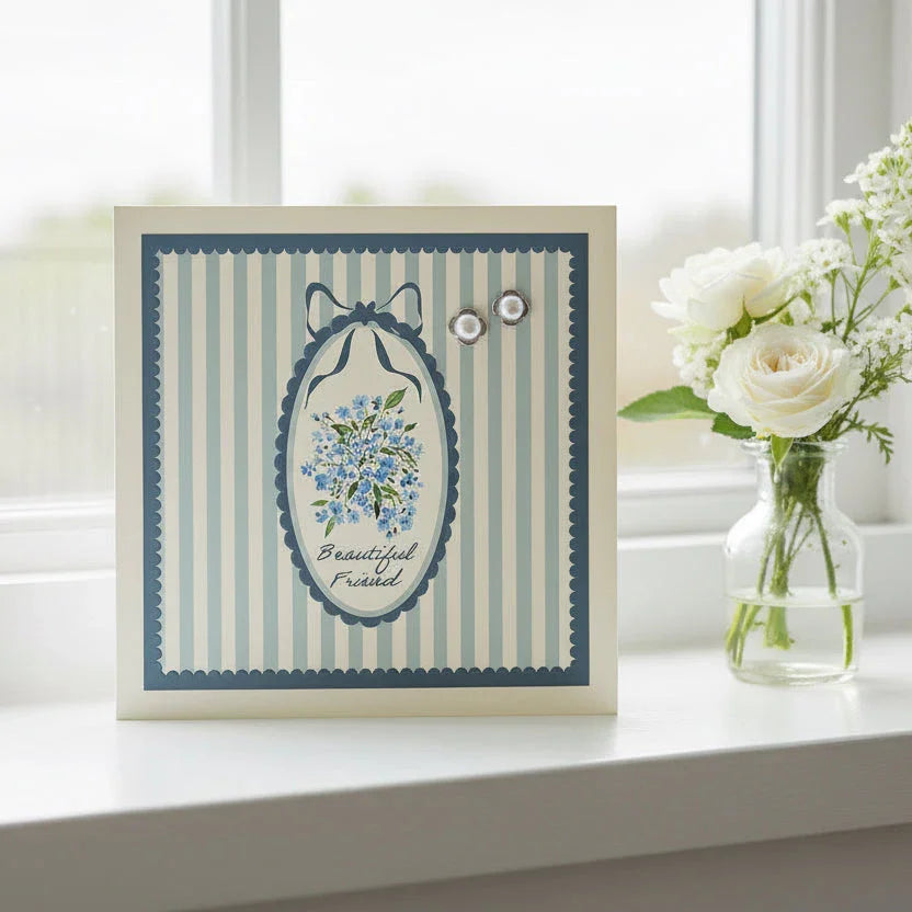 Beautiful friend card with blue floral design and pearl earrings, displayed by a window.