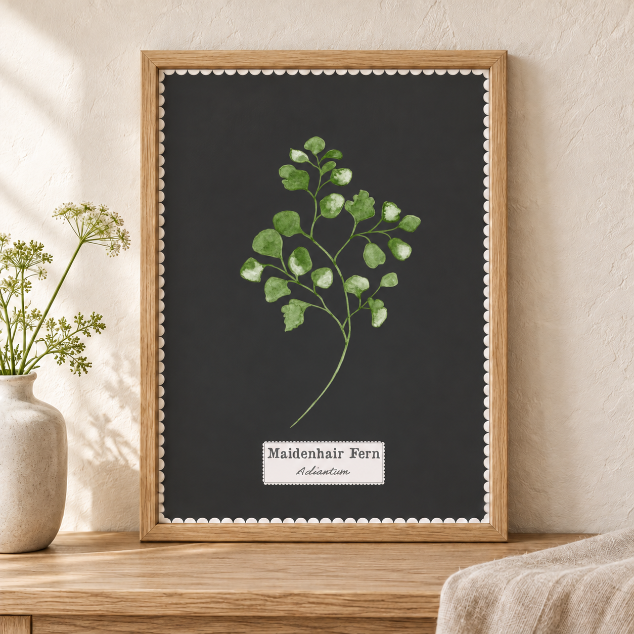 Maidenhair Fern botanical art print in a wooden frame on a shelf with a vase of flowers.