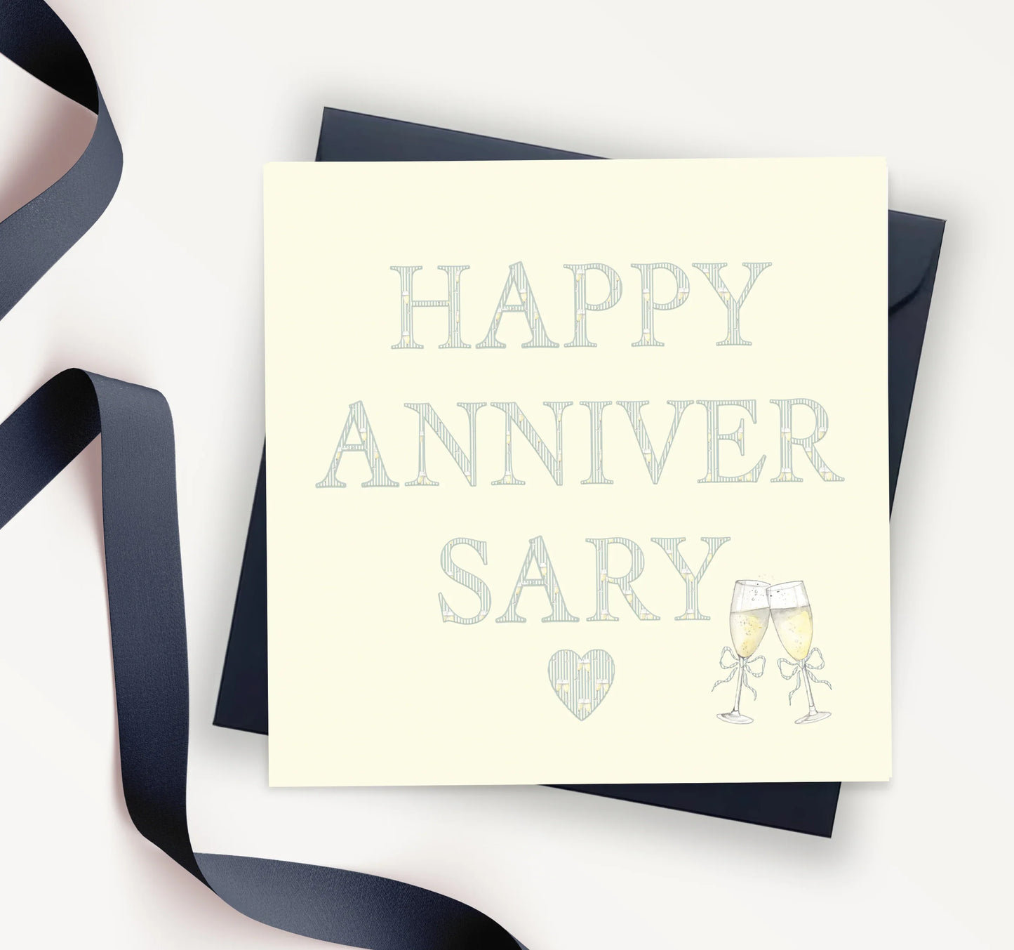 Happy anniversary card with two champagne glasses and a heart, navy ribbon and envelope