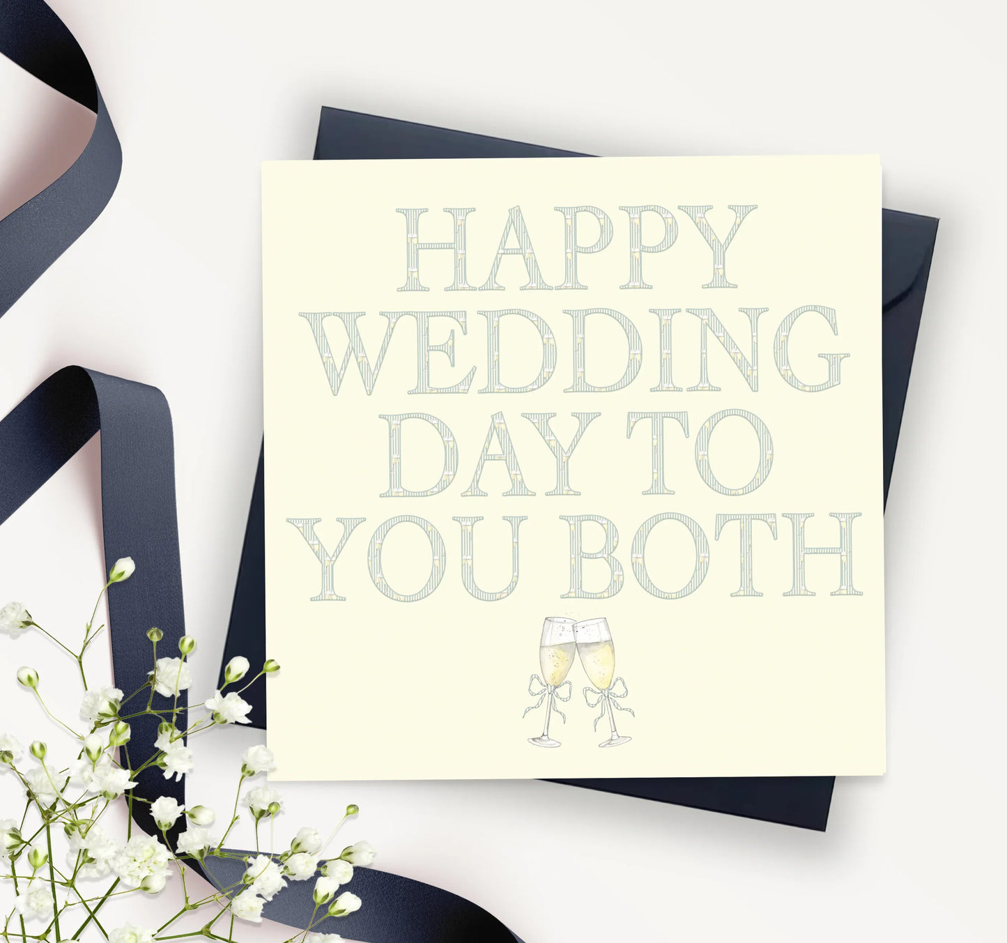 Happy wedding day greeting card with champagne glasses, navy envelope, ribbon, and flowers