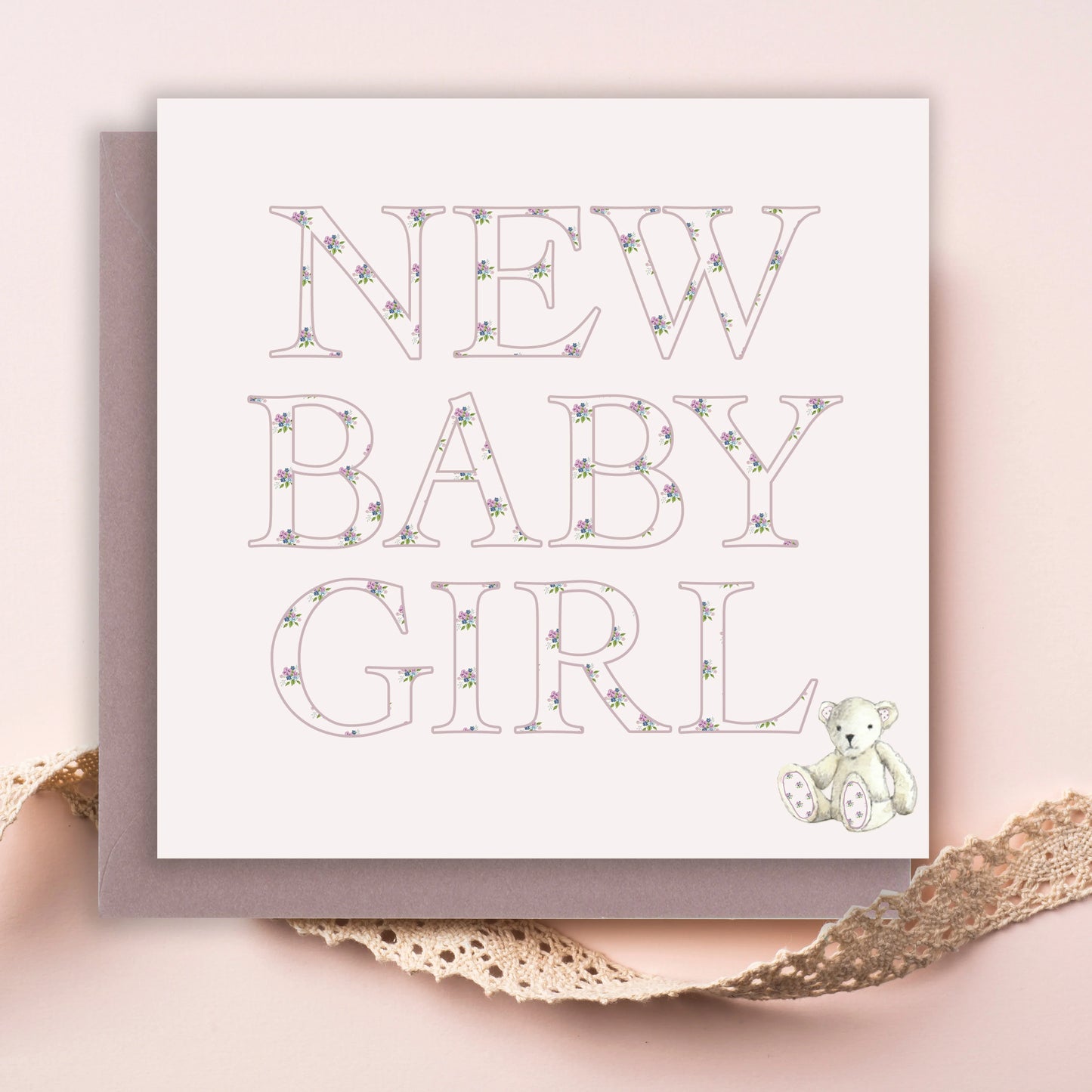 New baby girl card with floral lettering and illustrated teddy bear on pastel background