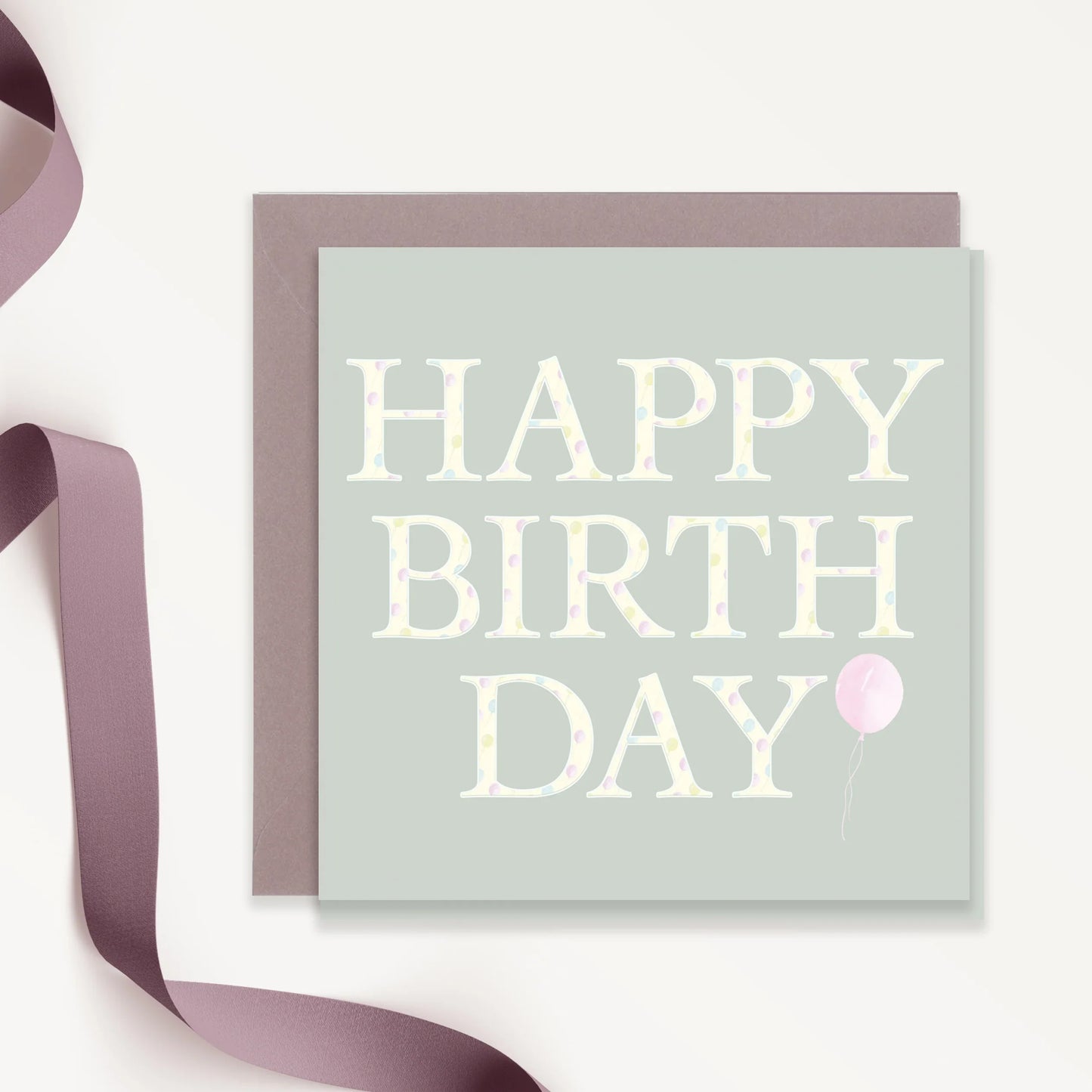 Happy birthday card with pastel polka dot text and pink balloon, lavender ribbon beside