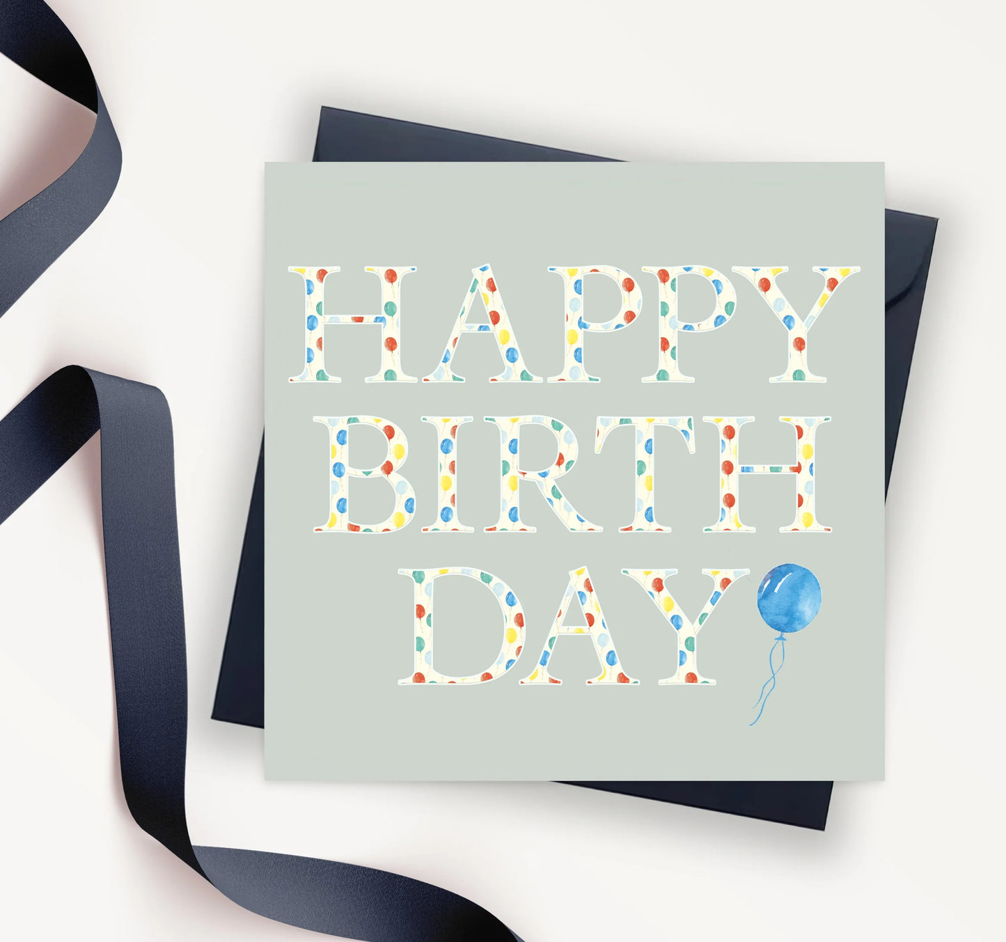 Polka dot happy birthday card with blue balloon and navy ribbon on light background