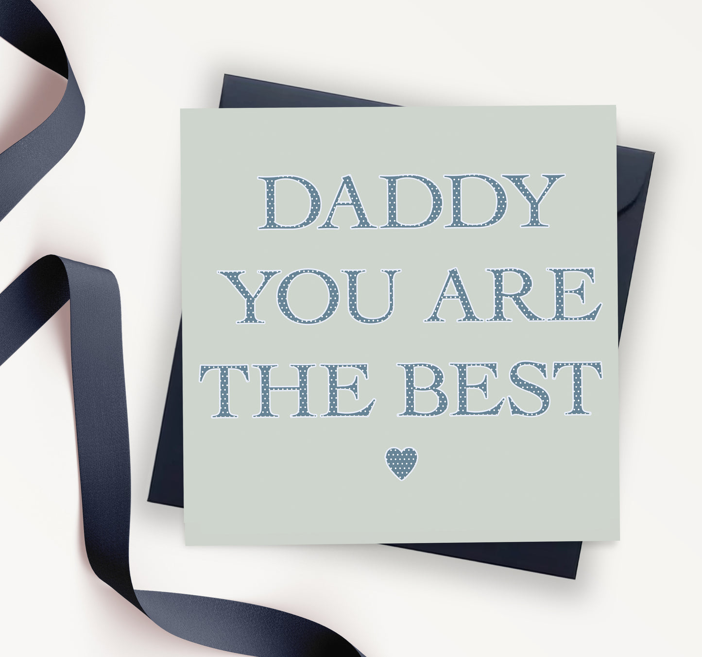 Greeting card with blue text 'Daddy you are the best' and a heart, navy ribbon and envelope