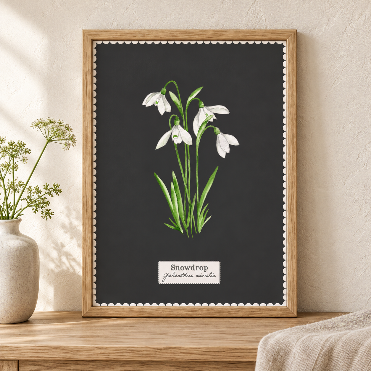 Snowdrop botanical art print in a wooden frame on a wooden surface